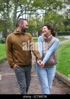 Glückliche Paare mittleren Alters, die im Frühling oder Herbst gemeinsam im Freien spazieren gehen, die Natur genießen und Zeit mit Spaziergängen verbringen und den Park erkunden. Stockfoto