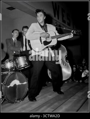 Elvis Presley trat 1956 mit seiner Band The Blue Moon Boys auf. Das Foto wurde 1956 aufgenommen, einem entscheidenden Jahr für Presleys Karriere, als er sein Debütalbum veröffentlichte und seine erste Nummer-Eins-Single Heartbreak Hotel hatte. Die im Bild sichtbaren Bandmitglieder sind Elvis Presley an der Gitarre, D.J. Fontana am Schlagzeug und Bill Black am Stand-up Bass. Stockfoto