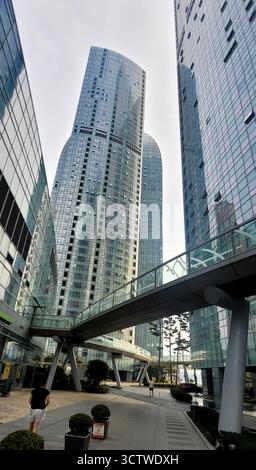 Ein Foto von Hochhäusern in Marine City, Busan, Südkorea, das die beeindruckende moderne Architektur aus glänzenden, glasverkleideten Gebäuden und einer Fußgängerbrücke einfängt. Marine City ist ein bekanntes Wohn- und Geschäftsviertel im Haeundae District, das auf zurückgewonnenem Land erbaut wurde und für seine luxuriösen Hochhäuser bekannt ist. Es ist zu einem Symbol für zeitgenössische Stadtentwicklung und wohlhabendes Leben in Südkorea geworden und bietet einen beeindruckenden Blick auf den Ozean. 2025. Stockfoto