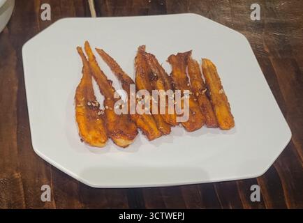 Ein Foto der traditionellen koreanischen Küche, ein Gericht mit kleinem, gebratenem oder geröstetem Fisch, der in einer Sauce überzogen und mit Sesamsamen bestreut ist, in Gyeongju, Südkorea. Die koreanische Küche, die für ihre kräftigen Aromen und oft scharfen Gerichte bekannt ist, bietet häufig Banchan (Beilagen) wie Myeolchi Bokkeum (gebratene Sardellen). 2025. Stockfoto