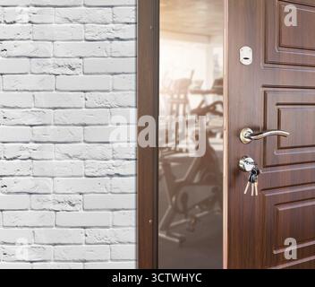 Zugang zum Fitnessstudio im Fitnessclub, offene Tür mit Heimtrainer Stockfoto