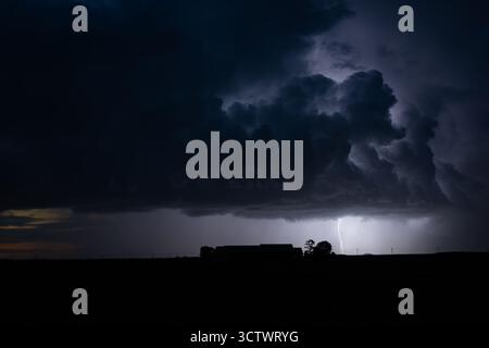 Stürmischer Nachtblitz über ländlicher Landschaft mit dunklen Wolken. Stockfoto
