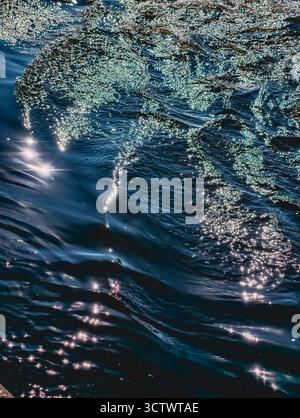 Funkelnde Ozeanwelle mit Sonnenlichtreflektionen - tiefblaue Meerwasser-Oberflächenstruktur für Natur- und Meditationshintergrund-Design Stockfoto