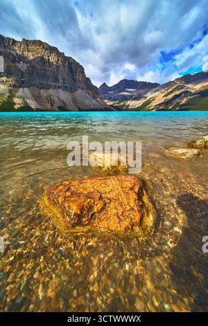 Bow Lake Crystal Water und Rocky Shore mit dramatischer Bergkette unter bewölktem Himmel Stockfoto