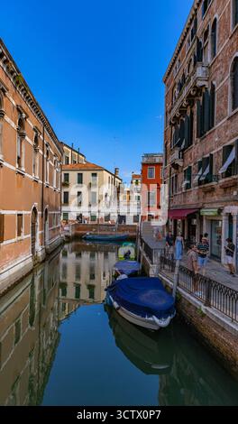Venedig, Italien - 23. Juli 2024: Boote ankern entlang eines engen venezianischen Kanals, gesäumt von historischen Gebäuden Stockfoto