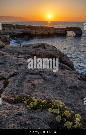 Goldener Sonnenuntergang über dem Arch of Skaleta mit felsigen Klippen, die im Abendlicht leuchten, und ruhigem Mittelmeer auf Kreta, Griechenland. Stockfoto