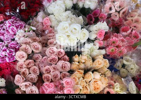 Bunte Blumensträuße (Rosen, Gerbera Daisies, Nelken), die auf einem Blumenmarkt ausgestellt werden. Verpacktes Arrangement zum Verkauf oder als Geschenk. Stockfoto
