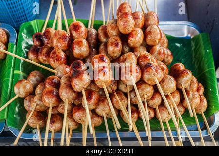 Nahaufnahme authentischer thailändischer fermentierter Schweinswurstspieße (Naem), gegrillt und auf einem Tablett serviert. Ein beliebter asiatischer Snack. Stockfoto