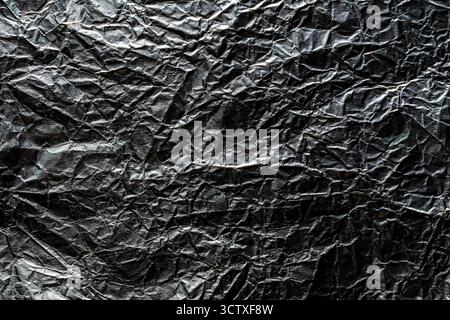 Hintergrund und Textur der gebrauchten zerknitterten Schokoladenfolie, Nahaufnahme, Draufsicht. Glänzende Aluminiumfolie ohne Schokoladenbonbons Stockfoto