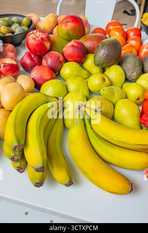 Lebensmittelfotografie mit kontrastierenden Texturen: Bananenschale, Birnenoberfläche, raue Avocadohaut, Kartoffelboden, samtige Nektarinen, und Feigen auf einem Sof Stockfoto