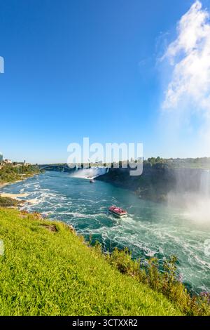 Ein pulsierender Panoramablick auf die American Falls bei den Niagara Falls, New York, mit der berühmten Rainbow Bridge, die die USA und Kanada in der verbindet Stockfoto