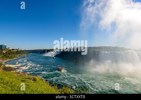 Ein pulsierender Panoramablick auf die American Falls bei den Niagara Falls, New York, mit der berühmten Rainbow Bridge, die die USA und Kanada in der verbindet Stockfoto
