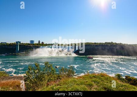 Ein pulsierender Panoramablick auf die American Falls bei den Niagara Falls, New York, mit der berühmten Rainbow Bridge, die die USA und Kanada in der verbindet Stockfoto