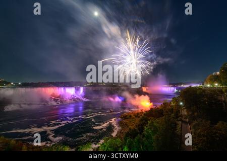 Ein spektakulärer Blick bei Nacht auf die Niagarafälle mit den kanadischen Horseshoe Falls und den American Falls, beleuchtet von einem lebhaften Feuerwerk. Stockfoto