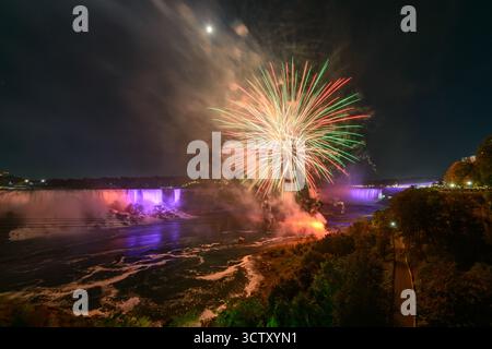 Ein spektakulärer Blick bei Nacht auf die Niagarafälle mit den kanadischen Horseshoe Falls und den American Falls, beleuchtet von einem lebhaften Feuerwerk. Stockfoto