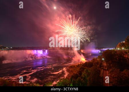 Ein spektakulärer Blick bei Nacht auf die Niagarafälle mit den kanadischen Horseshoe Falls und den American Falls, beleuchtet von einem lebhaften Feuerwerk. Stockfoto