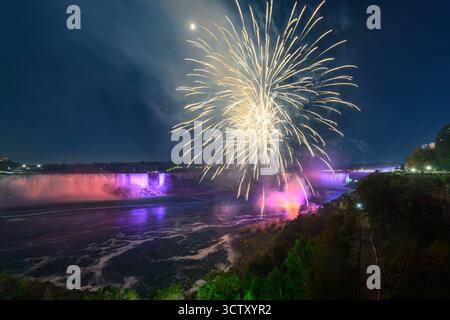 Ein spektakulärer Blick bei Nacht auf die Niagarafälle mit den kanadischen Horseshoe Falls und den American Falls, beleuchtet von einem lebhaften Feuerwerk. Stockfoto