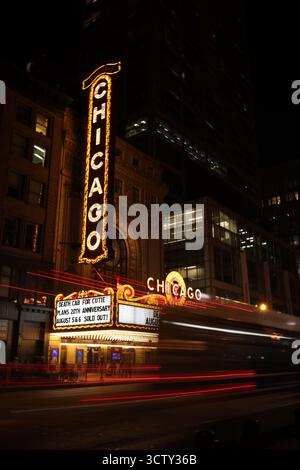 Das legendäre Chicago Theatre-Schild leuchtet nachts. Lange Belichtungsspuren vom Verkehr geben der lebhaften Stadtstraße Bewegung. Stockfoto