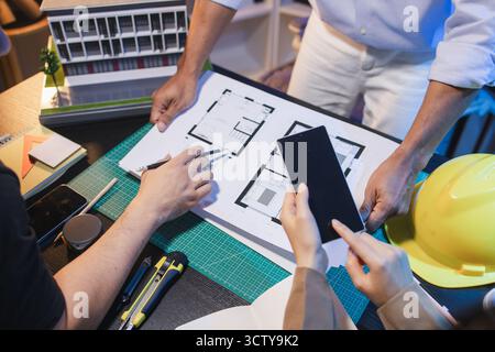 Eine Gruppe von Ingenieuren und Architekten arbeitet an einem Bauprojekt zusammen, diskutiert Ideen und teilt technische Pläne, um innovative moderne Bu zu entwerfen Stockfoto