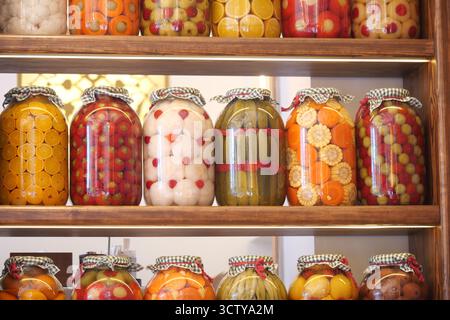 Gläser mit bunten Früchten und Gemüse in Regalen Stockfoto
