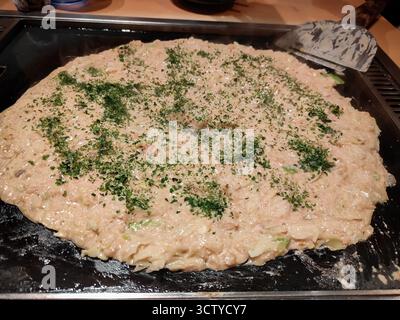 Traditionelles japanisches Okonomiyaki, das auf einem Teppan-Grill zubereitet wird, mit köstlicher Textur und authentischem Street Food-Stil. Stockfoto