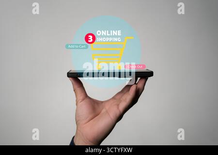 Handheld-Smartphone mit Online-Einkaufswagen-Symbol, das das Hinzufügen in den Warenkorb und das Bezahlen anzeigt, repräsentiert E-Commerce-Geschäft, digitalen Einzelhandel, mobile Payme Stockfoto