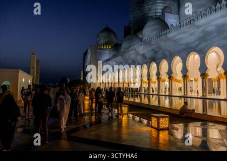Abu Dhabi berühmte Moschee in den Vereinigten Arabischen Emiraten - Scheich-Zayed-Moschee - mit beleuchteten Säulen und Kuppeln, die nachts im Wasser reflektiert werden Stockfoto