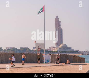 Beach Basketball Court in Abu Dhabi, VAE, mit Spielern unter der Nationalflagge in der Nähe der Großen Moschee und des hohen Turms. Stockfoto