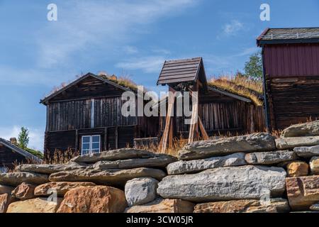 Hyttklokka diente als Glocke, um die Arbeitszeitpläne in der Smelthytta in Røros, Norwegen, zu signalisieren, die von historischen Rasendächern unter blauem Himmel umgeben ist Stockfoto