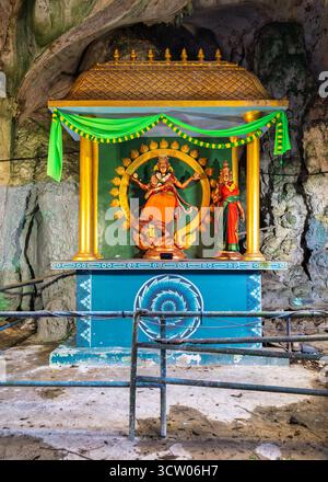 Hinduschrein mit goldenen Gottheiten und farbenfrohen Dekorationen in den Batu Caves, Gombak, Malaysia. Ein spiritueller Höhlentempel mit alten Felsformationen. Stockfoto