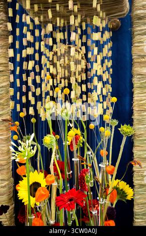 Dieses eindrucksvolle Bild zeigt eine lebendige und zeitgenössische florale Kunstinstallation mit einer eklektischen Mischung aus farbenfrohen Blüten, die einzeln aufgehängt werden Stockfoto