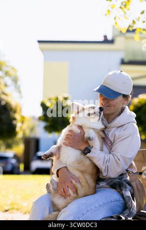 Eine Frau trainiert einen Hund auf einer Lichtung in einem Stadtpark. Ein Mädchen läuft mit einem Hund im Park. Süßer Corgi Pembroke, Hundeliebhaber Routine Stockfoto