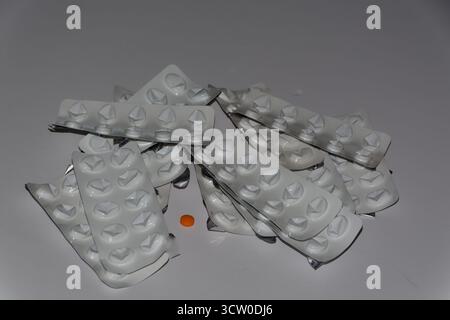 Einige gebrauchte und leere weiße Pillen Blisterpackungen - eine Probe orange Pille in der Mitte - zu viel Gebrauch von Pillen kann gefährlich sein. Stockfoto