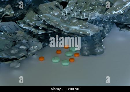 Ein Stapel gebrauchter und leerer Tabletten in Blisterpackungen – mit Proben oranger und grüner Tabletten – über die Einnahme von Pillen kann gefährlich sein. Stockfoto