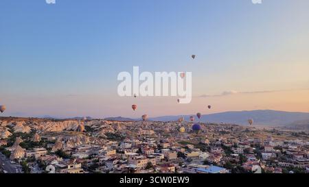 Das weltberühmte Spektakel von Dutzenden Heißluftballons, die während des Sonnenaufgangs friedlich über die einzigartige Landschaft von Göreme in Kappadokien, Türkei, schweben Stockfoto