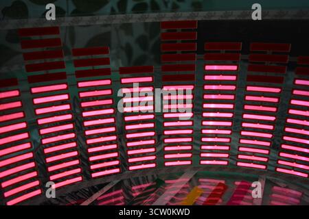 Roter, leuchtender Plastikaufkleber in Form eines echten Equalizers, der zur Musik aufblitzt. Viele rot leuchtende Quadrate auf weichem Kunststoffhintergrund, lebhaft, Stockfoto