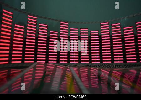 Roter, leuchtender Plastikaufkleber in Form eines echten Equalizers, der zur Musik aufblitzt. Viele rot leuchtende Quadrate auf weichem Kunststoffhintergrund, lebhaft, Stockfoto