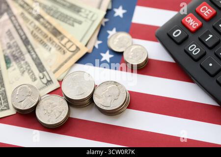 US-Dollar-Geldscheine und Taschenrechner auf amerikanischer Flagge Nahaufnahme. Geldinvestitionskonzept und Steuerzahlung Stockfoto