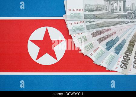Nordkoreaner gewannen Geldscheine in großer Höhe lügen auf der Flagge der Volksrepublik Korea aus nächster Nähe. Finanz- und Bankkonzept Stockfoto