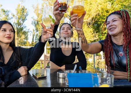 Freundinnen, die Drinks trinken, um die Freundschaft im Freien zu feiern Stockfoto
