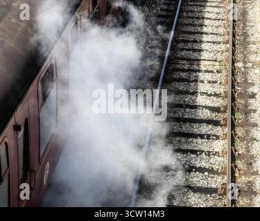 Traditioneller Eisenbahnwagen und Dampfpplume mit leerem Gleis Stockfoto