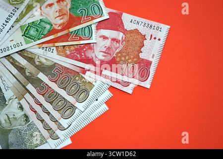 Pakistanische Rupien Banknoten auf rotem Hintergrund. Die aktuellen pakistanischen Geldrechnungen liegen in großer Höhe auf dem Tisch. Das Konzept des Geschäfts und der Investitionen in Pakistan Stockfoto