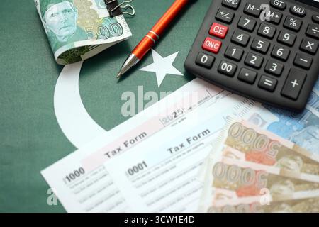 Pakistanische Rupien Banknoten mit Taschenrechner und Steuerformular. Die aktuellen pakistanischen Echtgeldrechnungen und Steuerpauschalen aus nächster Nähe. Das Konzept der Steuerzahlung und Buchhaltung in Pakistan Stockfoto