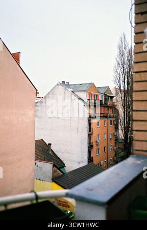 Analoges Foto von einem Balkon eines Gebäudes aus der sozialistischen Ära mit Blick auf ähnliche gelbe Backsteingebäude. Bedeckter Himmel. Dokumentarische Stadtarchitektur Stockfoto