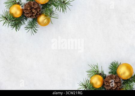 Blick von oben auf schneebedeckte Tannenzweige mit Tannenzapfen und gelbe weihnachtskugeln auf weißem Schneehintergrund mit Kopierraum. Flache Winterkomposition Stockfoto