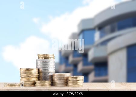 Gestapelte Münzen gegen Eigentumswohnungen. Geld sparen, um eine Wohnung zu kaufen Stockfoto