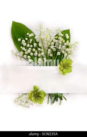 Blumenstrauß mit weißen Blüten Maiglöckchen ( Convallaria majalis, Maiglocken, Maiglöckchen), Hellebores und weiße Papierkarte mit Platz für Text Stockfoto