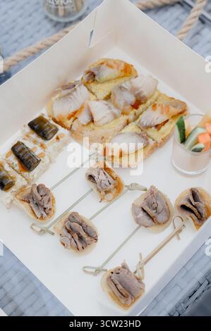 Nahaufnahme einer Reihe von Häppchen mit Fleisch, Fisch und Vorspeisen. Zu den Vorspeisen des Buffets gehören Häppchen und Sandwiches mit geräuchertem Fisch. Stockfoto