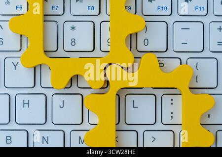 Gelbe Zahnradformen auf einer Computertastatur symbolisieren Automatisierung in Computersystemen, digitale Arbeitsabläufe und technologische Prozessintegration. Stockfoto