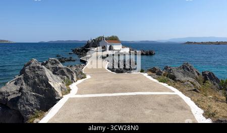 Agios Isidoros kleine Kirche, Insel Chios, Griechenland. Traditionelle Architekturkapelle auf einer felsigen Insel, die durch einen schmalen Betonwalkw mit dem Ufer verbunden ist Stockfoto